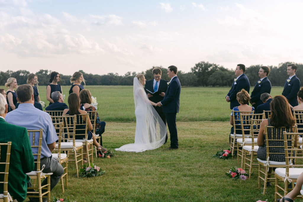 Halletsville wedding on family ranch with cream, white and ivory decor. Field kissing photo. 