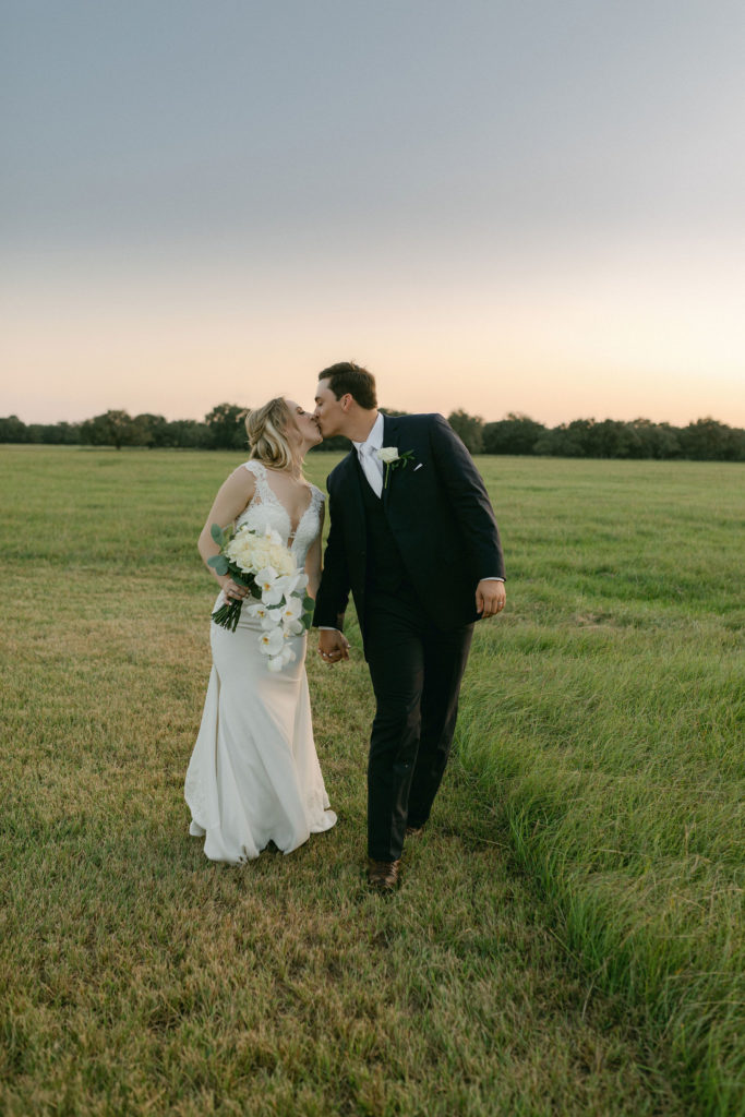 Halletsville wedding on family ranch with cream, white and ivory decor. Field kissing photo. 
